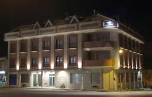 un grand bâtiment avec une lumière sur son côté dans l'établissement Hostal Jijones, à Villarrubia de los Ojos