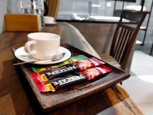 a tray with a cup of coffee and a packet of candy at BK Hotel in Phnom Penh