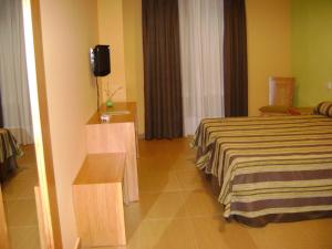 Habitación de hotel con cama y TV en Hostal Jijones en Villarrubia de los Ojos