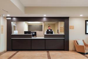 a man standing at a reception desk in a lobby at Candlewood Suites Lenexa - Overland Park Area by IHG in Lenexa
