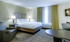 a hotel room with a bed and a chair and a table at Candlewood Suites Lakeville I-35 by IHG in Lakeville