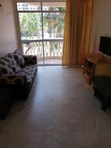uma sala de estar com um sofá e uma grande janela em Apartment at Glory Beach Resort em Porto Dickson