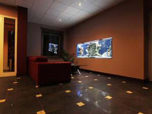 a waiting room with a red chair and a large screen tv at Hotel Otoliński in Płock