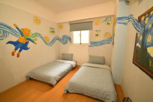 duas camas num quarto com um mural na parede em Dong Gang Li Yuan Homestay em Donggang