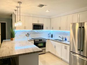 una cucina con armadi bianchi e frigorifero in acciaio inossidabile di MODERN SPACIOUS BEACH FRONT CENTRAL CONDO w POOLS STEPS TO BEACH a Rosarito