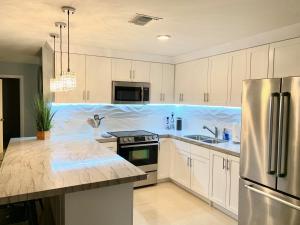 a kitchen with white cabinets and a stainless steel refrigerator at BEACHFRONT CONDO w POOLS STEPS TO BEACH & MINS TO DT in Rosarito