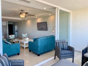 un soggiorno con divani blu, tavolo e sedie di MODERN SPACIOUS BEACH FRONT CENTRAL CONDO w POOLS STEPS TO BEACH a Rosarito