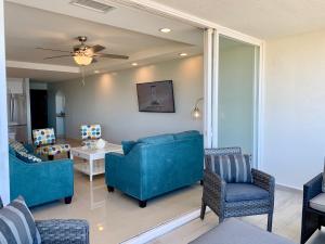 a living room with blue couches and a table and chairs at BEACHFRONT CONDO w POOLS STEPS TO BEACH & MINS TO DT in Rosarito