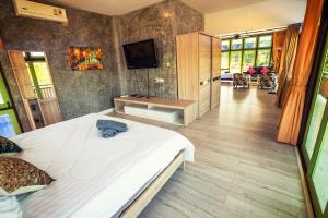 a bedroom with a large bed and a tv on the wall at Tonmai Suites in Ko Lanta