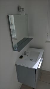 uma casa de banho branca com um lavatório e um espelho em T4 centre Lourdes em Lourdes