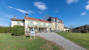 a large house with a sign in front of it at Hotel Helios - Golf in Salies-de-Béarn