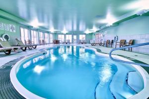 a large swimming pool in a building with tables and chairs at Holiday Inn Express Hotel & Suites Dieppe Airport, an IHG Hotel in Moncton