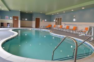 Holiday Inn Express & Suites Raleigh Airport - Brier Creek, an IHG Hotel في رالي: مسبح كبير في غرفة مستشفى مع كراسي برتقالية