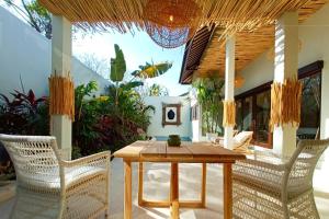 een patio met een houten tafel en stoelen bij Nunamkhalu Private Villa and Spa in Nusa Dua