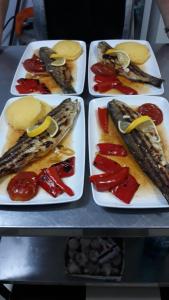 tres platos de comida en una mesa con pescado y pimientos en Moara Viselor, en Vaideeni
