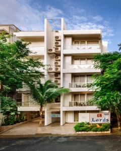 a white building with a palm tree in front of it at Lords Eco Inn Bengaluru Jayanagar in Bangalore