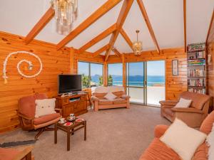a living room filled with furniture and a tv at Picturesque on Paku - Tairua Holiday Home in Tairua