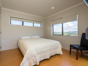 una camera con un letto e una sedia e una finestra di Driftwood Views - Mangawhai Heads Holiday Home a Mangawhai