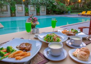 una mesa con platos de comida junto a una piscina en Phuwanalee Resort, en Mu Si
