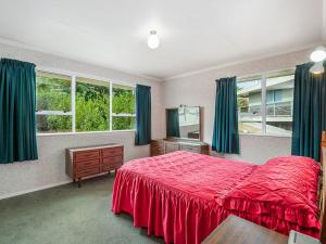 a bedroom with a red bed and green curtains at Kinloch Family Retreat - Kinloch Holiday Home in Kinloch