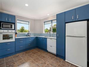 a kitchen with blue cabinets and a white refrigerator at Kinloch Family Retreat - Kinloch Holiday Home in Kinloch