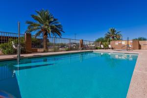 une grande piscine bleue avec des palmiers et une clôture dans l'établissement Candlewood Suites Tucson, an IHG Hotel, à Tucson