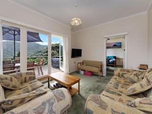 a living room with two couches and a table at Surfer's Sunshine Cottage - Piha Holiday Home in Piha