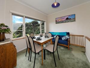 uma sala de jantar com uma mesa e cadeiras e um sofá em Surfer's Sunshine Cottage - Piha Holiday Home em Piha