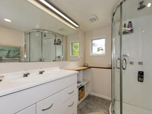 un baño con lavabo y ducha en Surfer's Sunshine Cottage - Piha Holiday Home, en Piha 11 fotos más