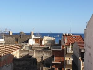 einen Blick auf die Dächer von Gebäuden mit dem Meer im Hintergrund in der Unterkunft Caccia Apartment in Santa Teresa di Riva