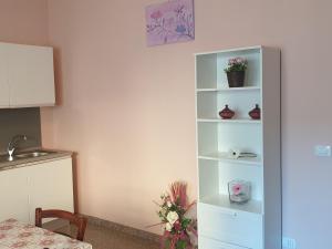 ein weißes Bücherregal mit Blumen und Vasen darauf in der Unterkunft Caccia Apartment in Santa Teresa di Riva
