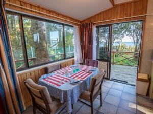 a dining room with a table and chairs and windows at Matai Cottage - Pakawau Bach in Pakawau