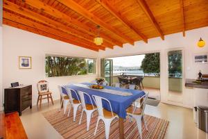 a dining room with a blue table and chairs at Waterfront Bach - Raglan Bach in Raglan