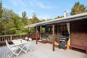 a deck with a table and chairs and a grill at Piwakawaka ā Pukawa - Pukawa Bay Holiday Home in Kuratau