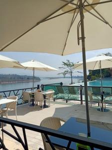 a deck with tables and chairs and umbrellas at Chiangkhong Teak Garden Riverfront Onsen Hotel- SHA Extra Plus in Chiang Khong