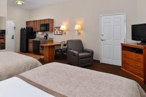 a hotel room with a bed and a chair and a kitchen at Candlewood Suites Turlock, an IHG Hotel in Turlock
