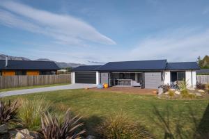 a house with a blue roof and a yard at Paradise Found - Lake Hawea Holiday Home in Lake Hāwea