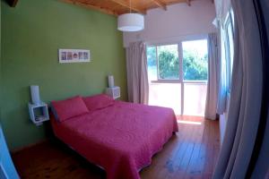 a bedroom with a pink bed and a large window at Altos de la Costa - Gualeguaychú in Gualeguaychú