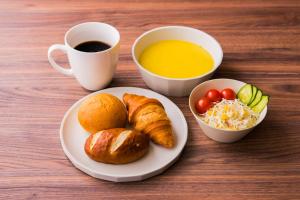 una mesa con un plato de cruasanes y una taza de café en The Celecton Matsumoto, en Matsumoto