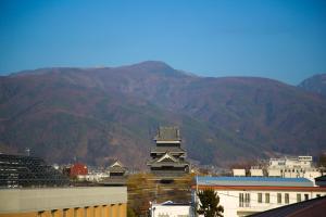 a tall building with mountains in the background at The Celecton Matsumoto in Matsumoto
