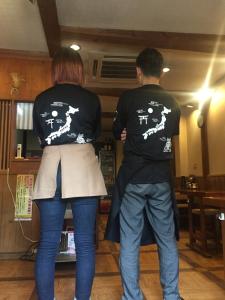 un hombre y una mujer de pie en una cocina jugando un videojuego en Guest house daisho oshiro asobi, en Matsue