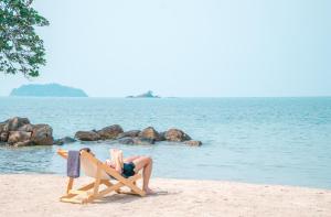 a woman laying in a beach chair reading a book at VAYNA Boutique Koh Chang in Ko Chang