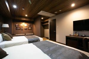 a hotel room with two beds and a flat screen tv at The Celecton Matsumoto in Matsumoto