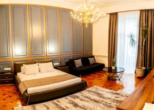 um quarto com uma cama, um sofá e um lustre em Matei Corvin Apartment em Cluj-Napoca