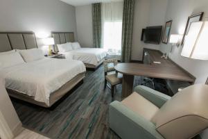 a hotel room with two beds and a couch at Candlewood Suites - McDonough, an IHG Hotel in McDonough