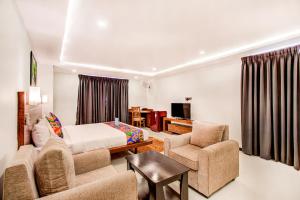 1 dormitorio con cama, sofá y sillas en FabHotel The Royal Suites, en Bangalore