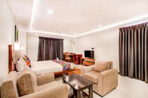 a bedroom with a bed and a couch and chairs at FabHotel The Royal Suites in Bangalore