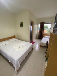 Un dormitorio con una gran cama blanca y una ventana en HOTEL GUAIRACÁ en Guarapuava