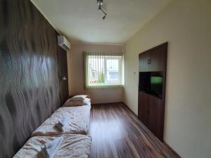 a room with two beds and a television in it at Ladik Vendégház in Tiszafüred