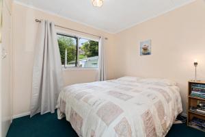 Schlafzimmer mit einem Bett und einem Fenster in der Unterkunft The Taranui Cottage - Mangawhai Heads Holiday Home in Mangawhai